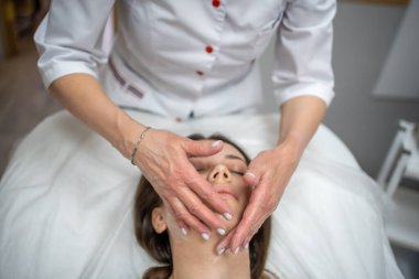 Yüz masajı. Güzellik kliniğinde kadın kozmetik uzmanı tarafından yüz temizleme ameliyatındaki kadın portresi. Güzellik endüstrisi konsepti. 
