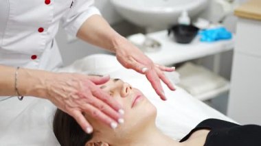 Yüz masajı. Güzellik kliniğinde kadın kozmetik uzmanı tarafından yüz temizleme ameliyatındaki kadın portresi. Güzellik endüstrisi konsepti. 