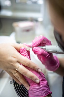 Manikür sanatçısı güzellik salonunda profesyonel manikür yapıyor.