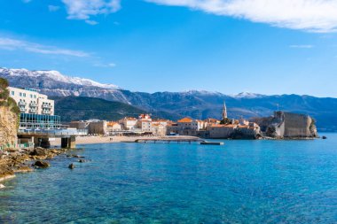 Budva, Karadağ - 28 Şubat 2022: Eski Budva kasabasının plajı. Karadağ 'ın Budva kentinin antik duvarları ve kiremitli çatısı