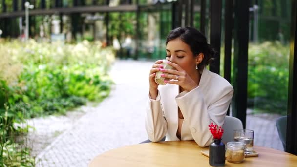 在城市街头咖啡馆里 年轻的女商人边喝咖啡边喝着咖啡 美丽的女工在布拉格街上等客人的画像 高质量的4K镜头 — 图库视频影像