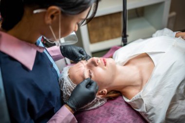 Makyaj uzmanı, modelin yeni kaşları için ölçüler alıyor. Mikro patinaj hazırlığı. Yüksek kalite fotoğraf