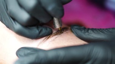 Kaş mikropatinajı prosedürü. Siyah eldivenli bir usta kaş modellerinin karışımından bir iğne yapıyor. Yüksek kalite 4k görüntü