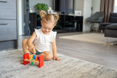 Beyaz, sevimli bir kız. Evinde yerde eko tahta oyuncaklarla oynuyor. Montessori oyuncağı. Eğitici oyunlar oynayan çocuk. Yüksek kalite fotoğraf