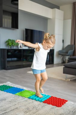 Küçük kız masaj minderinde yürüyor. Bebek bebek ayak masajı minderi. Ortopedik masaj halısı için egzersiz. Yüksek kalite fotoğraf