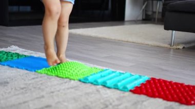 Küçük kızın masaj minderinde yürüyüşünü yakından izle. Bebek bebek ayak masajı minderi. Ortopedik masaj halısı için egzersiz. Yüksek kalite 4k görüntü