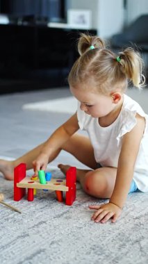 Cute caucasian little girl playing on the floor at home with eco wooden toys. Montessori toy. The child playing educational games. High quality 4k footage