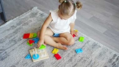Cute caucasian little girl playing on the floor at home with eco wooden toys. Montessori toy. The child playing educational games. High quality 4k footage