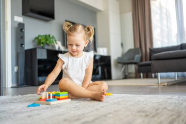 Beyaz, sevimli bir kız. Evinde yerde eko tahta oyuncaklarla oynuyor. Montessori oyuncağı. Eğitici oyunlar oynayan çocuk. Yüksek kalite fotoğraf