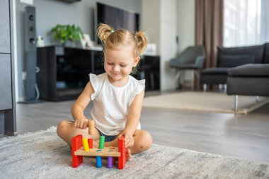 Beyaz, sevimli bir kız. Evinde yerde eko tahta oyuncaklarla oynuyor. Montessori oyuncağı. Eğitici oyunlar oynayan çocuk. Yüksek kalite fotoğraf