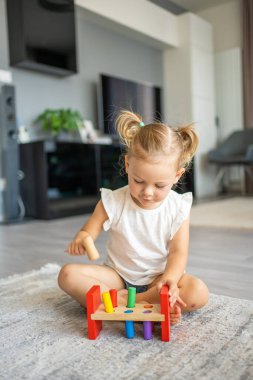 Beyaz, sevimli bir kız. Evinde yerde eko tahta oyuncaklarla oynuyor. Montessori oyuncağı. Eğitici oyunlar oynayan çocuk. Yüksek kalite fotoğraf