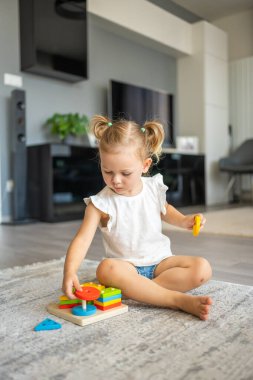 Beyaz, sevimli bir kız. Evinde yerde eko tahta oyuncaklarla oynuyor. Montessori oyuncağı. Eğitici oyunlar oynayan çocuk. Yüksek kalite fotoğraf