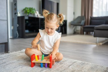 Beyaz, sevimli bir kız. Evinde yerde eko tahta oyuncaklarla oynuyor. Montessori oyuncağı. Eğitici oyunlar oynayan çocuk. Yüksek kalite fotoğraf