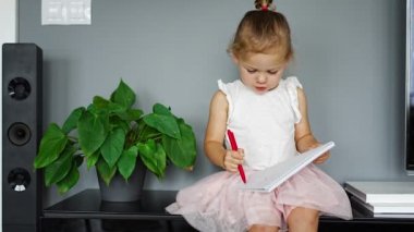 Little girl draw or write by red pencil at home. Child creativity and education concept. High quality 4k footage