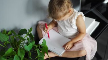 Little girl draw or write by red pencil at home. Child creativity and education concept. High quality 4k footage