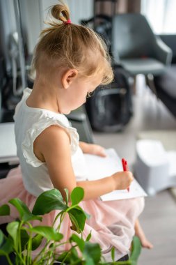 Little girl draw or write by red pencil at home. Child creativity and education concept. High quality photo