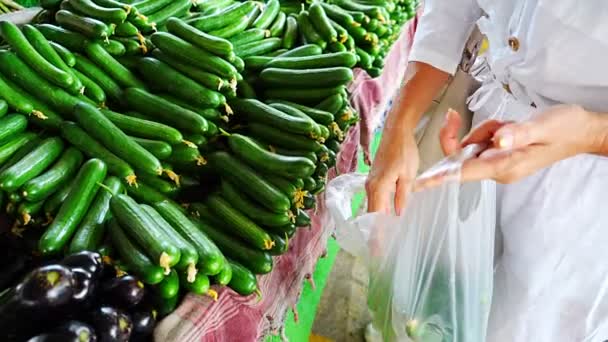 Eine Kundin Wählt Gurken Und Steckt Sie Eine Plastiktüte Auf — Stockvideo