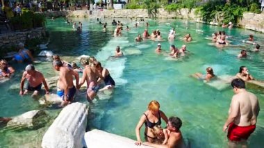 Pamukale, Türkiye - 14 Eylül 2022: Pamukkale, Türkiye 'de antik havuz Cleopatras Hamamı' nın tadını çıkaran turistler. Yüksek kalite 4k görüntü