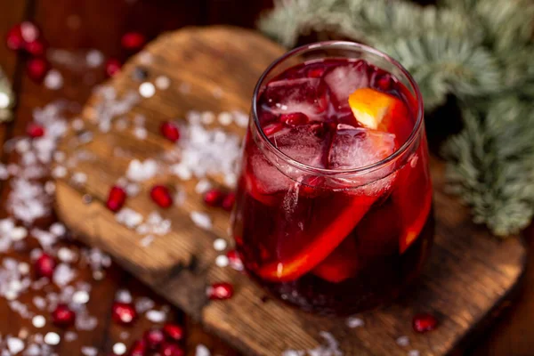 Склянка гранатового коктейлю з апельсином на фоні різдвяних прикрас і вогнів. Святковий зимовий напій Ліцензійні Стокові Зображення