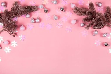 Soyut Noel arkaplanı pembeyle. Pembe konfeti, Noel baloları ve pembe arka planda köknar dalları, metin için kopyalama alanı