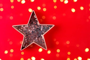  Kırmızı arka planda konfeti olan yıldız şeklinde bir kutu. Şenlikli Noel ve yeni yıl geçmişi