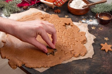 El hamurdaki kurabiyeleri keser. Noel kurabiyeleri yapma süreci. Baharatlı kurabiyeler için malzemeler