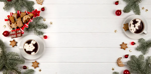 Beyaz ahşap bir zemin üzerine kurulmuş iki fincan marşmelov ve Noel kurabiyesi. Metin için kopya alanı olan web sitesi için pankart