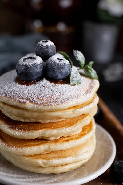 Masanın üzerinde yabanmersinli ev yapımı krep ve pudra şekeri var.