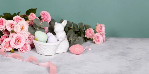 Easter bunny, colored eggs and pink flowers. Festive easter web banner with free text space — стоковое фото