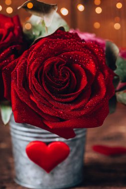 Sevgililer Günü tebrik kartı ve mesaj için boş yer. Kırmızı gül saksıda ve kırmızı kalpler tahta arka planda dikey fotoğrafta.