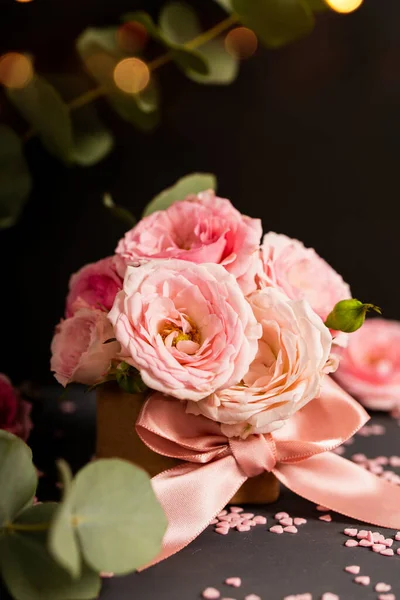 A bouquet of delicate pink roses in a box. Festive vertical card with pink flowers on a dark background, copy space for text — ストック写真