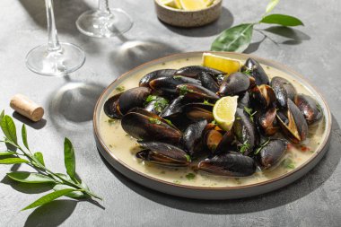 Sarımsak soslu siyah midye, otlar, limon ve yaz güneşinin altındaki masada iki bardak beyaz şarap.