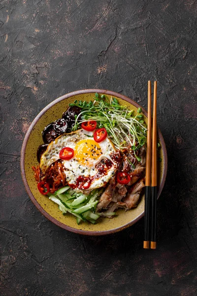 Geleneksel Kore yemeği Bibimbap. Pirinçli kase, şitake mantarı, tavuk, salatalık, mikroçerez ve Kore bibimbap sosu. Koyu arkaplan, dikey fotoğraf Stok Fotoğraf