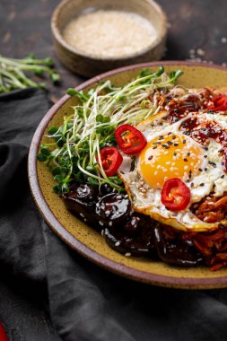 Geleneksel Kore yemeği Bibimbap. Pirinç, şitake mantarı, tavuk, salatalık, mikroçerez ve Kore bibimbap sosu. Koyu arkaplan, dikey fotoğraf
