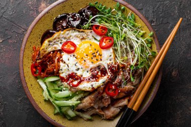 Geleneksel Kore yemeği Bibimbap. Pirinç, şitake mantarı, tavuk, salatalık, mikroçerez ve Kore bibimbap sosu ile birlikte en güzel manzarayı kapatın. Koyu arkaplan, 