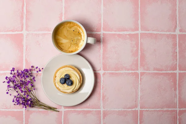 Чашка кави, торт і фіолетові квіти на рожевому тлі вид зверху. Вітальна листівка для жінок — стокове фото