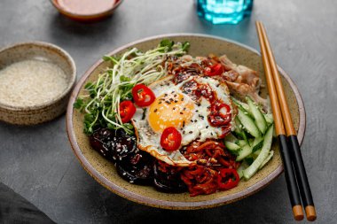 Geleneksel Kore yemeği Bibimbap. Pirinçli kase, şitake mantarı, tavuk, salatalık, mikroçerez ve Kore bibimbap sosu. Koyu arkaplan, metin için boşluk kopyala