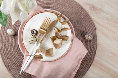  Boho tarzında Paskalya sofrası. Paskalya masasında tabak, çatal bıçak ve bıldırcın yumurtası.