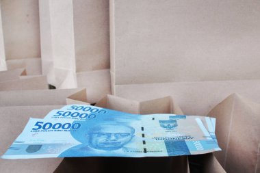 Arka planda bir sürü kese kağıdı olan kahverengi bir kesekağıdına elli bin rupi.