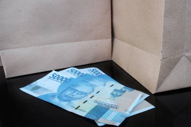 Siyah masadaki kağıt torbaların arasında yaklaşık 50 bin rupiah var.