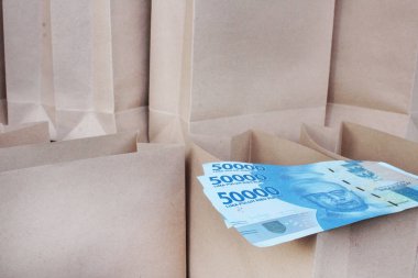 Bir sürü kağıt torba arasında açık kahverengi bir kesede elli bin rupi.