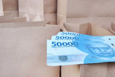 Elli bin rupiayı kağıt torbaların arasında açık kahverengi bir kesekağıdına koy.