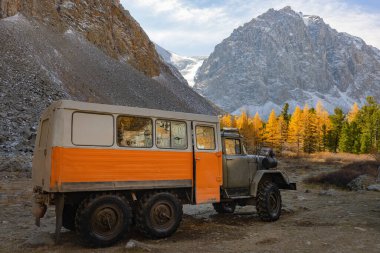Off-road kamyonu, dağlar, sarı tarlalar ve bir buzulun arkasında duruyor. Turizm ve seyahat. Rusya, Altai.