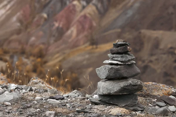 Dağların arkasındaki dağın tepesinde meditasyon için bir taş piramit. Uyum.