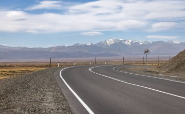 Sonbaharda bir dağ sırasının arka planındaki dağ vadisinde işaretli bir yol..