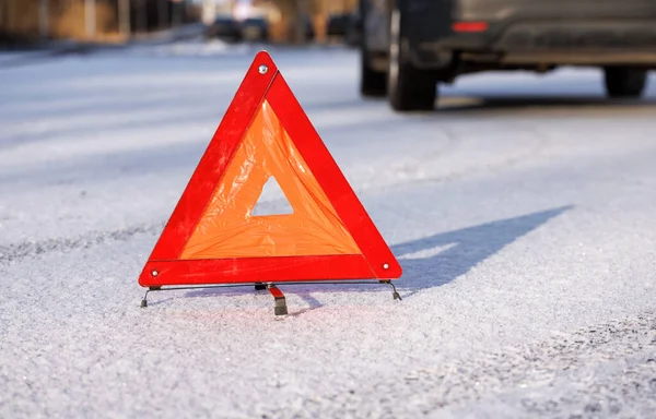 Il triangolo rosso di una sosta di emergenza su una strada invernale al posto di un arresto di auto. C'è una sagoma di un'auto sullo sfondo. Foto Stock