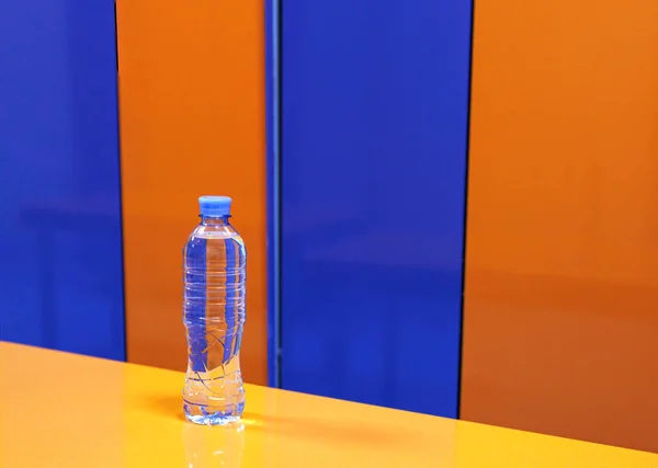 Spor salonundaki soyunma odasında mavi ve turuncu dolapların arka planında duran bir su şişesi..