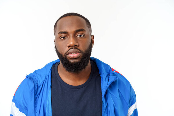 Молодой афроамериканец в спортивной одежде беззаботно одет на белом фоне.