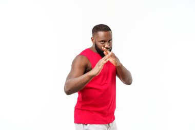 Genç kaslı Afro-Amerikan erkek boksörün portresi kenara bakıyor, yumrukluyor, gri arka planda tek başına duruyor. Spor, spor, vücut geliştirme..