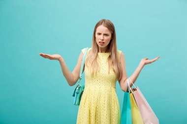 İndirimli satış konsepti: sarı şık elbiseli, alışveriş çantalı güzel, mutsuz genç kadın..